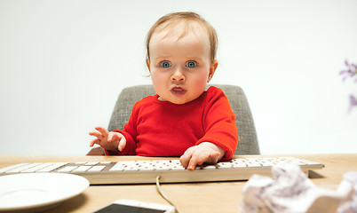 Image showing Happy child baby girl toddler sitting with keyboard of computer isolated on a white background