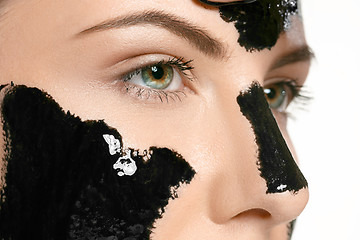 Image showing Young beautiful woman applying a mask for the face of the therapeutic black mud. Spa treatment