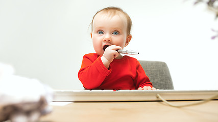 Image showing Happy child baby girl toddler sitting with keyboard of computer isolated on a white background