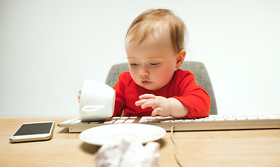 Image showing Happy child baby girl toddler sitting with keyboard of computer isolated on a white background