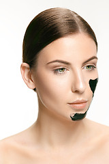 Image showing Young beautiful woman applying a mask for the face of the therapeutic black mud. Spa treatment