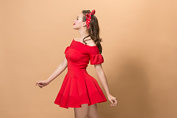 Image showing Beautiful young woman with pinup make-up and hairstyle. Studio shot on pastel background