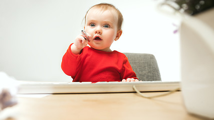 Image showing Happy child baby girl toddler sitting with keyboard of computer isolated on a white background