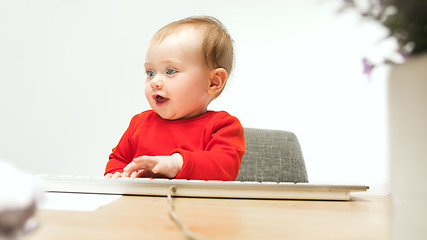 Image showing Happy child baby girl toddler sitting with keyboard of computer isolated on a white background