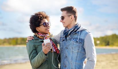 Image showing couple with smartphone and earphones over beach