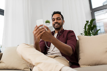 Image showing man in earphones listening to music on smartphone