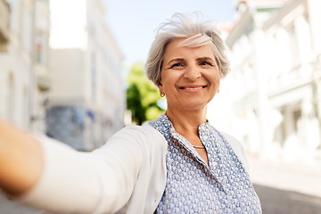 Image showing happy senior woman taking selfie on city street