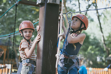 Image showing little brother and sister make climbing in the adventure park.