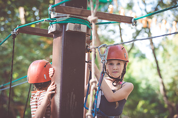 Image showing little brother and sister make climbing in the adventure park.