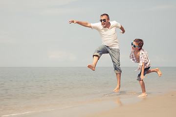 Image showing Father and son playing on the beach at the day time.