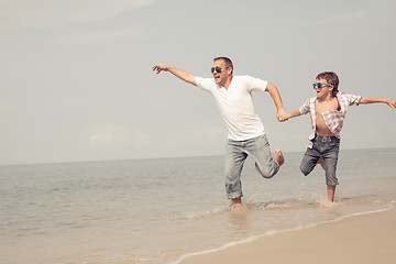 Image showing Father and son playing on the beach at the day time.