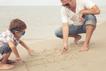 Image showing Father and son playing on the beach at the day time.