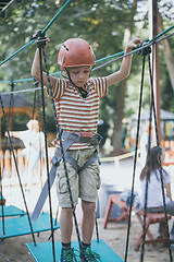 Image showing little boy make climbing in the adventure park. 