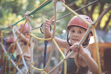 Image showing little brother and sister make climbing in the adventure park.