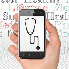Image showing Health concept: Hand Holding Smartphone with Stethoscope on display