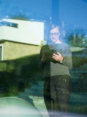 Image showing Woman using tablet at home by the window