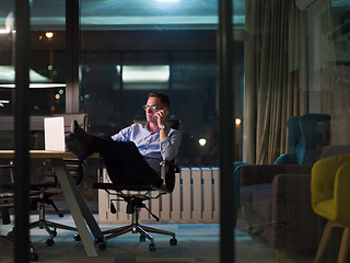 Image showing businessman using mobile phone in dark office