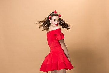 Image showing Beautiful young woman with pinup make-up and hairstyle. Studio shot on pastel background