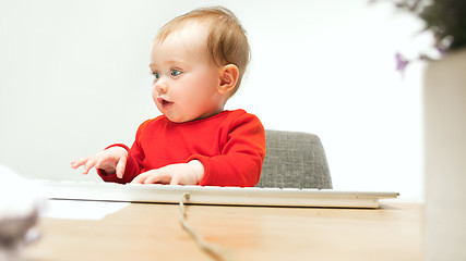 Image showing Happy child baby girl toddler sitting with keyboard of computer isolated on a white background