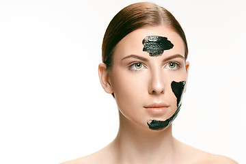 Image showing Young beautiful woman applying a mask for the face of the therapeutic black mud. Spa treatment