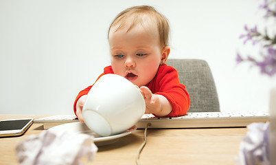 Image showing Happy child baby girl toddler sitting with keyboard of computer isolated on a white background