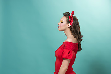 Image showing Beautiful young woman with pinup make-up and hairstyle. Studio shot on pastel background