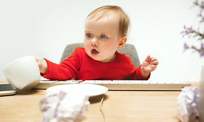 Image showing Happy child baby girl toddler sitting with keyboard of computer isolated on a white background