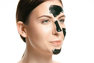 Image showing Young beautiful woman applying a mask for the face of the therapeutic black mud. Spa treatment