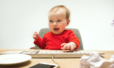 Image showing Happy child baby girl toddler sitting with keyboard of computer isolated on a white background