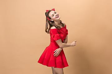 Image showing Beautiful young woman with pinup make-up and hairstyle. Studio shot on pastel background