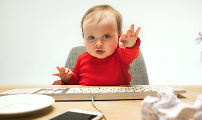 Image showing Happy child baby girl toddler sitting with keyboard of computer isolated on a white background