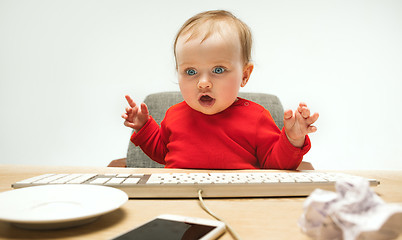 Image showing Happy child baby girl toddler sitting with keyboard of computer isolated on a white background