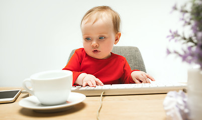 Image showing Happy child baby girl toddler sitting with keyboard of computer isolated on a white background