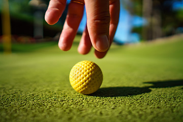 Image showing Mini Golf yellow ball on green grass at sunset