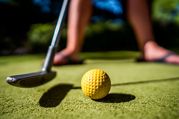 Image showing Mini Golf yellow ball with a bat near the hole at sunset