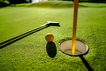 Image showing Mini Golf yellow ball with a bat near the hole at sunset