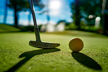 Image showing Mini Golf yellow ball with a bat near the hole at sunset