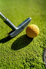 Image showing Mini Golf yellow ball with a bat near the hole at sunset