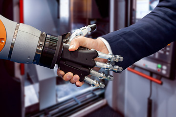 Image showing Hand of a businessman shaking hands with a Android robot.