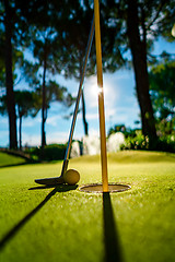 Image showing Mini Golf yellow ball with a bat near the hole at sunset