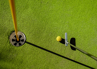 Image showing Mini Golf yellow ball with a bat near the hole at sunset