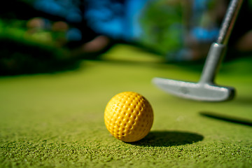 Image showing Mini Golf yellow ball with a bat near the hole at sunset