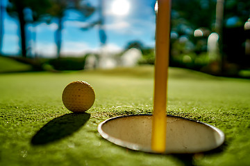 Image showing Mini Golf yellow ball on green grass at sunset