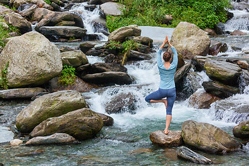 Image showing Woman in yoga asana Vrikshasana tree pose at waterfall outdoors