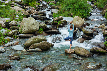 Image showing Woman in yoga asana Vrikshasana tree pose at waterfall outdoors