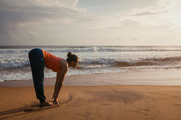 Image showing Woman doing yoga Sun salutation Surya Namaskar on beach