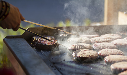 Image showing Chef preparing burgers at the barbecue outdoors