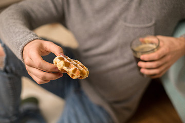 Image showing close up of man eating waffle with coffee at home