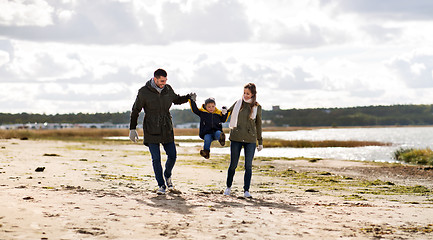 Image showing happy family walking along autumn beach