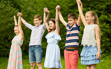 Image showing happy kids holding raised hands in summer park